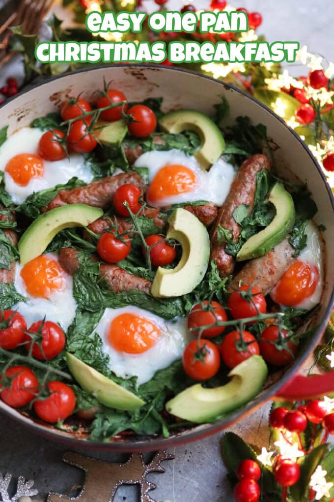 One Pan Christmas Breakfast in a large round red oven proof dish in with twinkly lights and Christmas decorations surrounding it. 