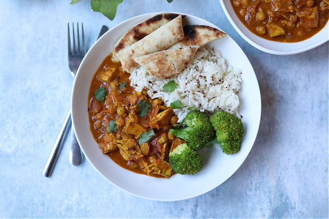 Leftover turkey curry served in a white bowl with white rice, broccoli and naan bread