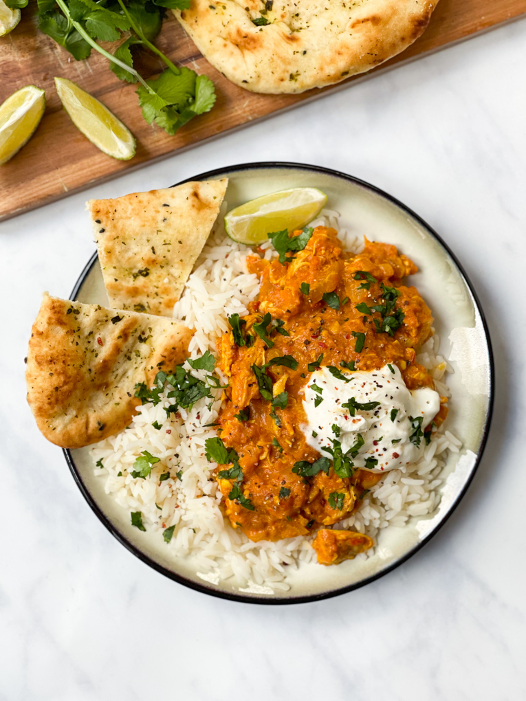 Slow Cooker Chicken Tikka Masala served with naan bread on a bed of white rice and garnished with coriander.