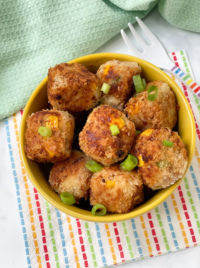 tuna sweetcorn bites in a yellow bowl topped with spring onion