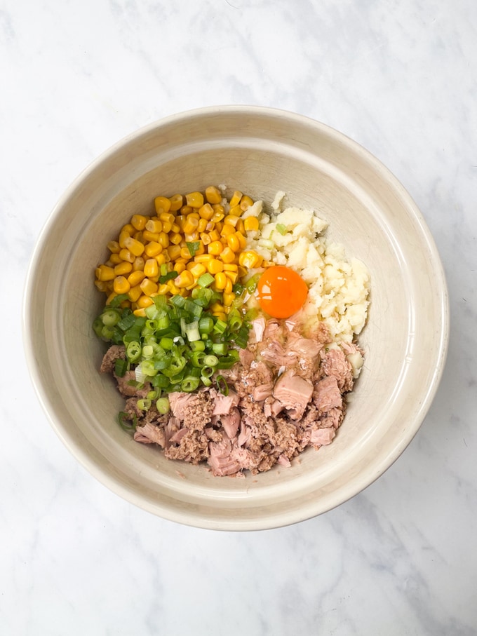 cold mashed potato, tuna, sweetcorn spring onion, panko breadcrumbs and an egg in a mixing bowl