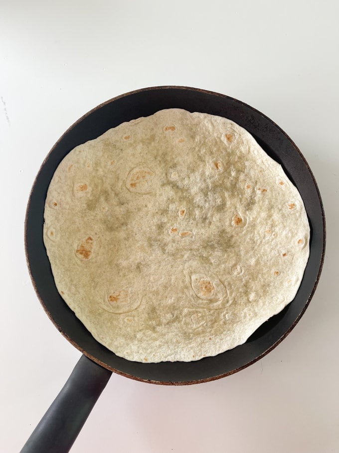 Tortilla wrap added to frying pan.