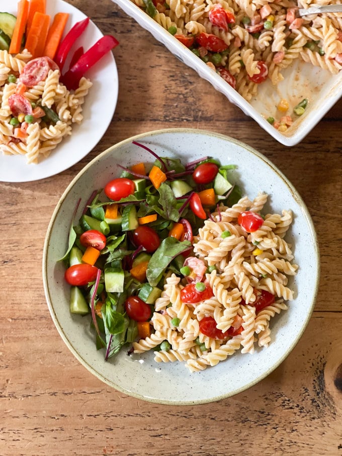 Baked cream cheese pasta served in a bowl alongside a side serving of mixed salad.