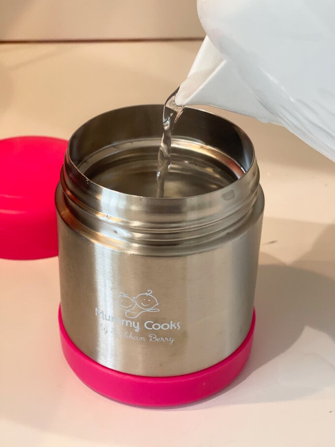 pouring kettle boiled water into the food flask to warm it up