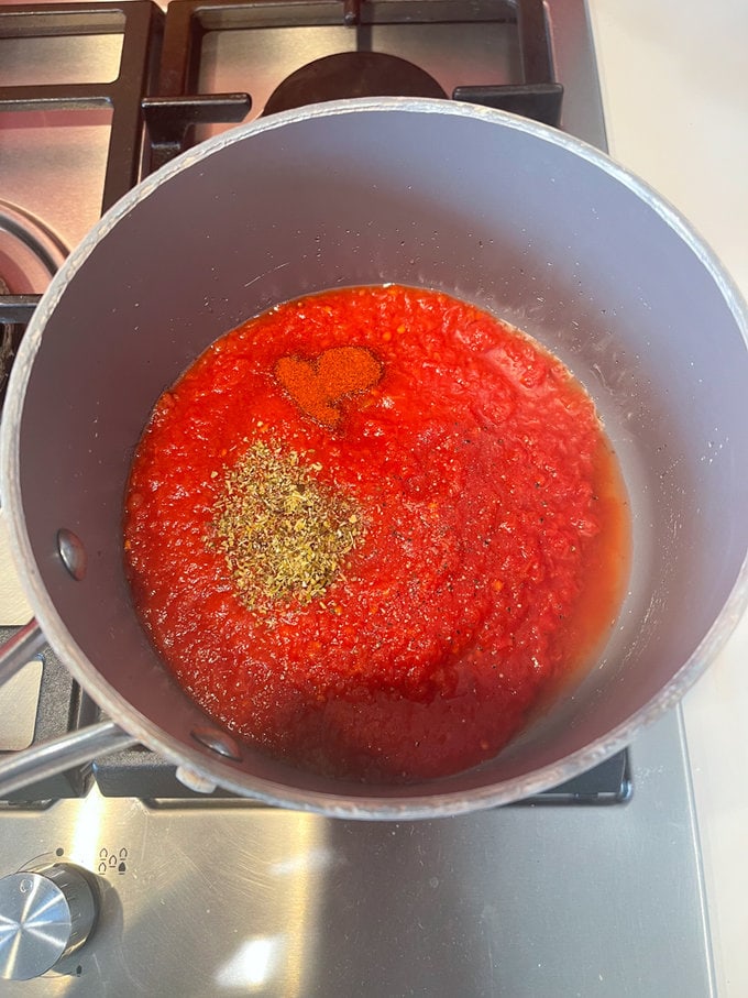 the chopped tomatoes, dried oregano, smoked paprika and a little salt in another saucepan on the hob