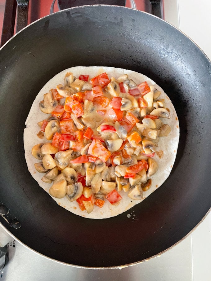 Cooked ingredients placed on top of a small tortilla in the frying pan. 