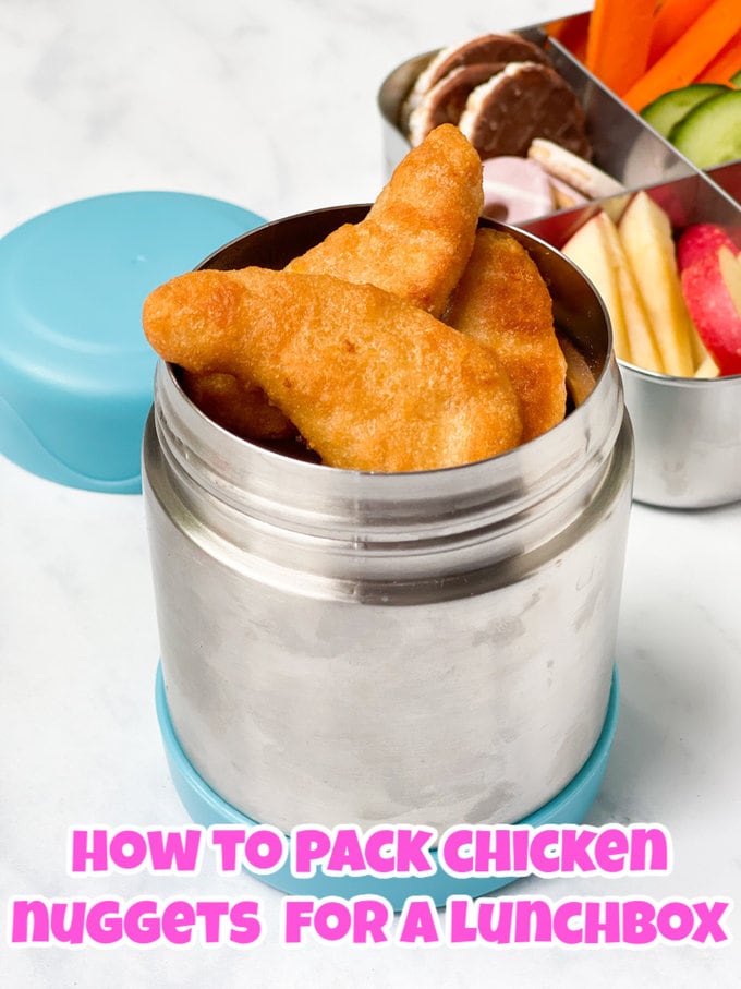 Chicken nuggets in a small thermos with a packed school lunch box in the background.