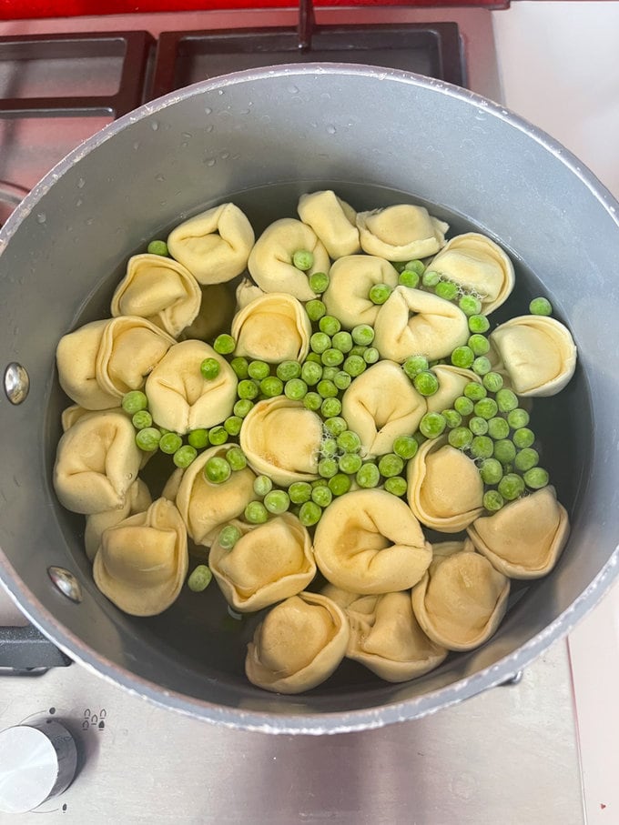 Tortellini and peas are added to a pan of water.