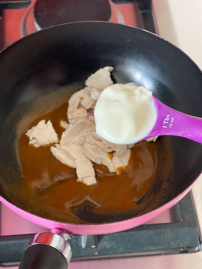 Cooked chicken and creme fraiche being added to the pan.