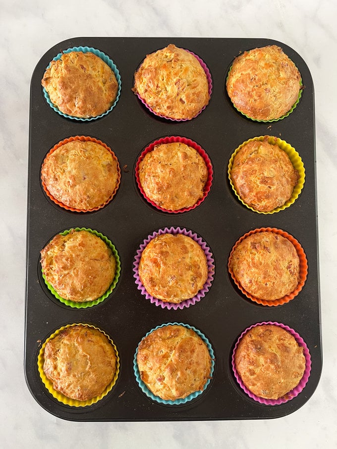 Muffins fresh out of the oven, presented in colorful cupcake cases on a baking tray.