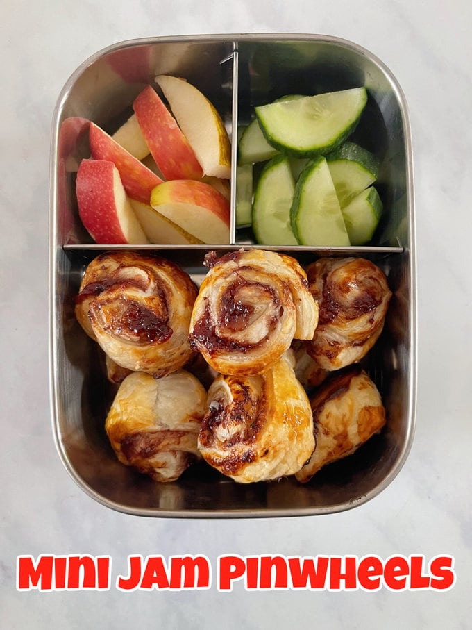 Mini Jam Pinwheels in a stainless steel compartment lunchbox with apple and cucumber slices.