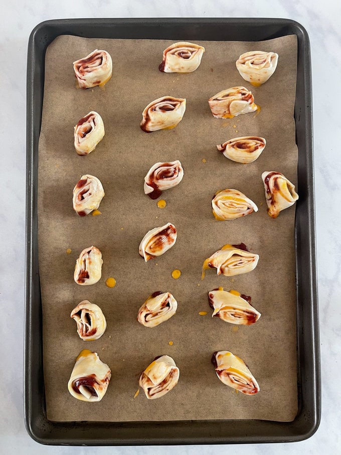 Pin wheels rolled and ready for the oven, presented on an oven tray.