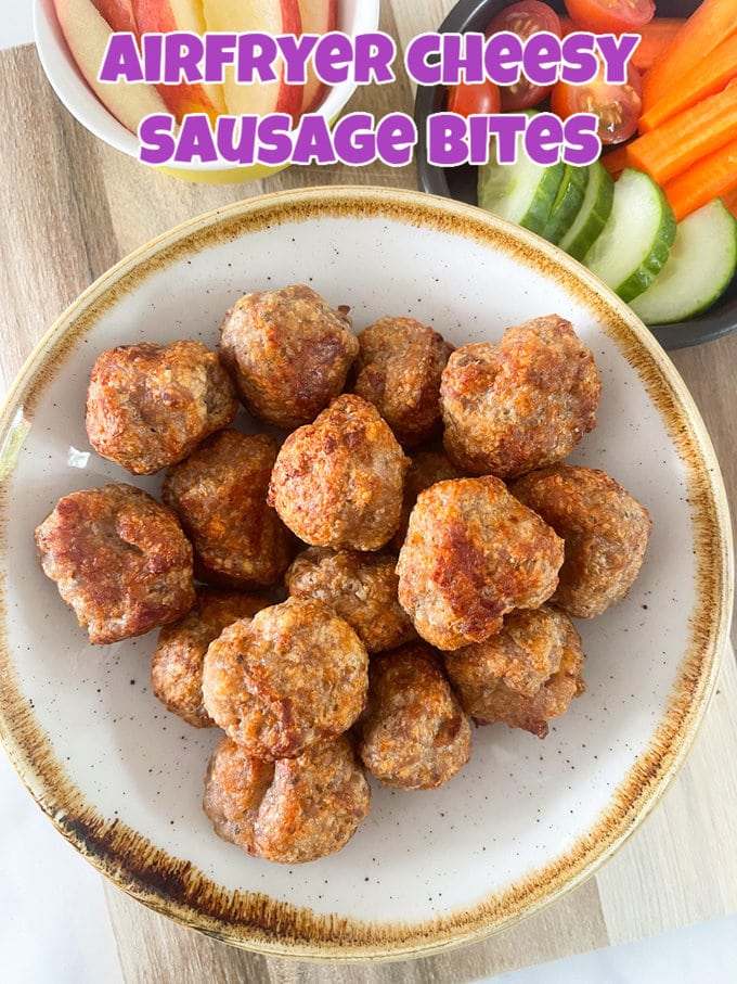 Airfryer cheesy sausage bites served in a bowl with bowls of chopped fruit and veggies in the background