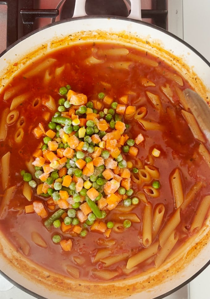 Chopped frozen vegetables being added to the same pan.