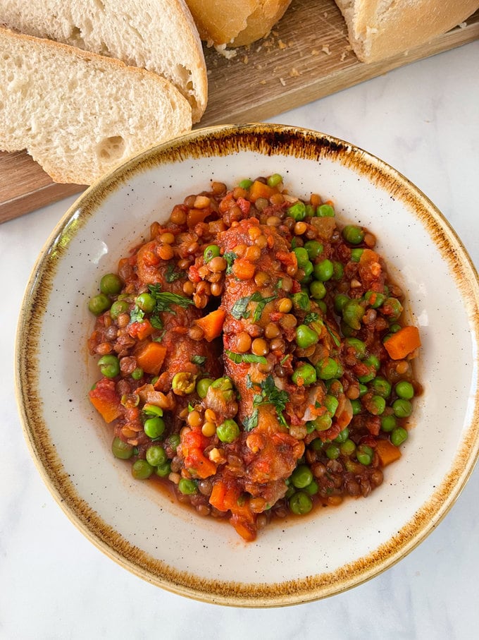 Slow cooker sausage and lentil casserole presented on a plate and garnished with fresh chopped parsley.