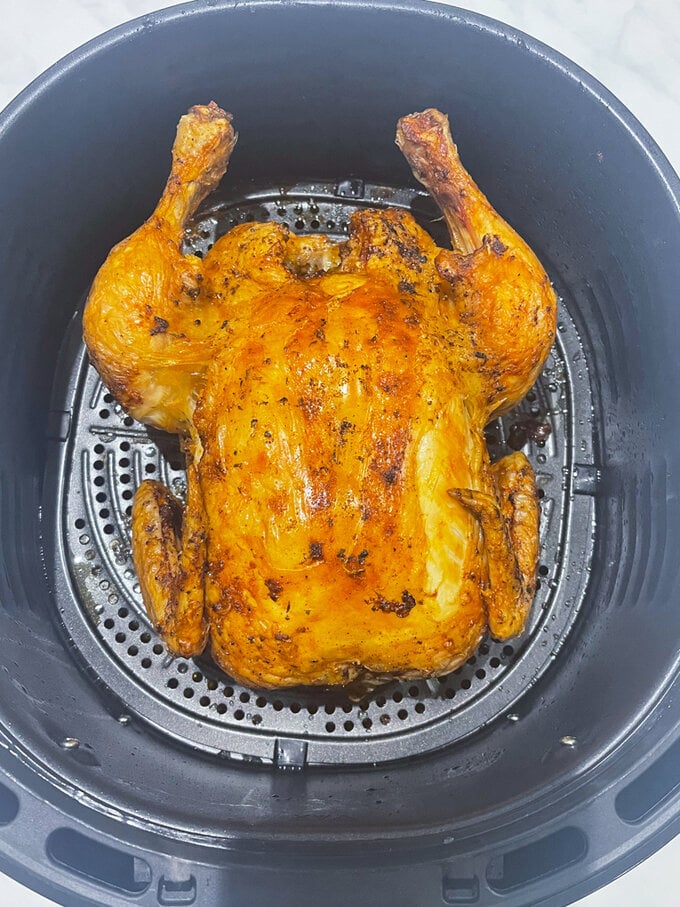 Crispy airfryer chicken sitting in the airfryer draw all cooked and golden brown.