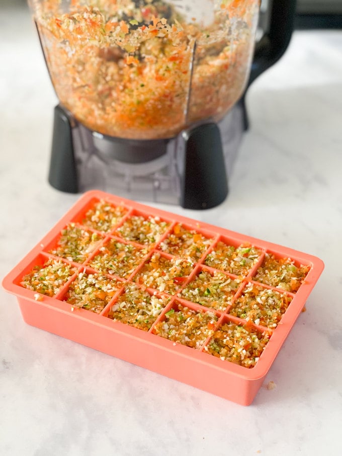 Blitzed vegetables presented in a pink ice cube tray, ready for the freezer.