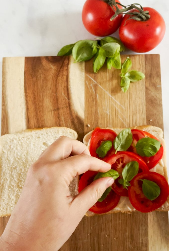 Tomatoes and basil being added to bread.