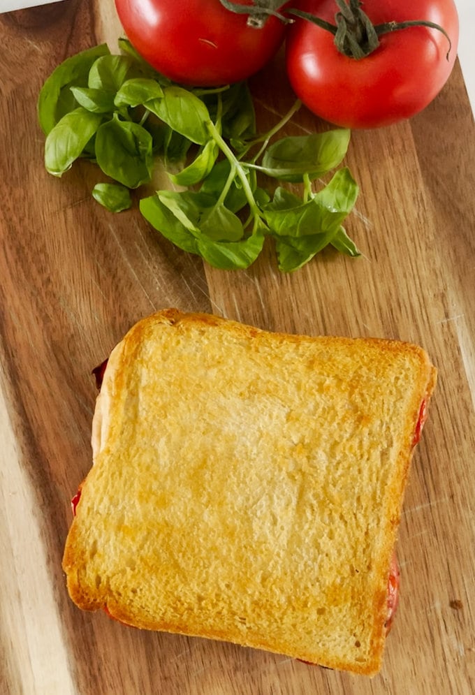 Cooked and golden brown toastie presented on a wooden chopping board. 