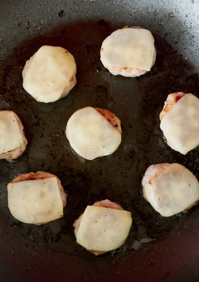 Small slices of cheese being added to the meatballs.