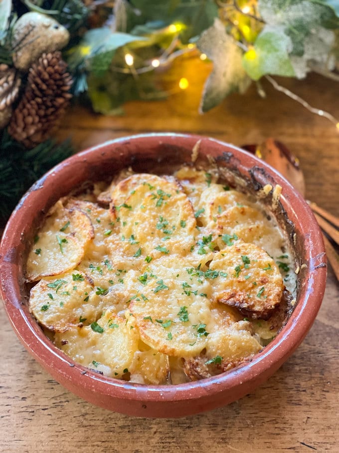 Airfryer dauphinoise potatoes, golden brown and presented in a round over proof dish, garnished with fresh parsley.