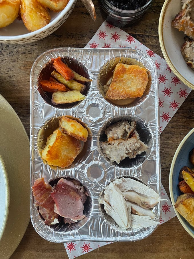 A silver foil muffin tin, full to the brim of Christmas day leftovers. 