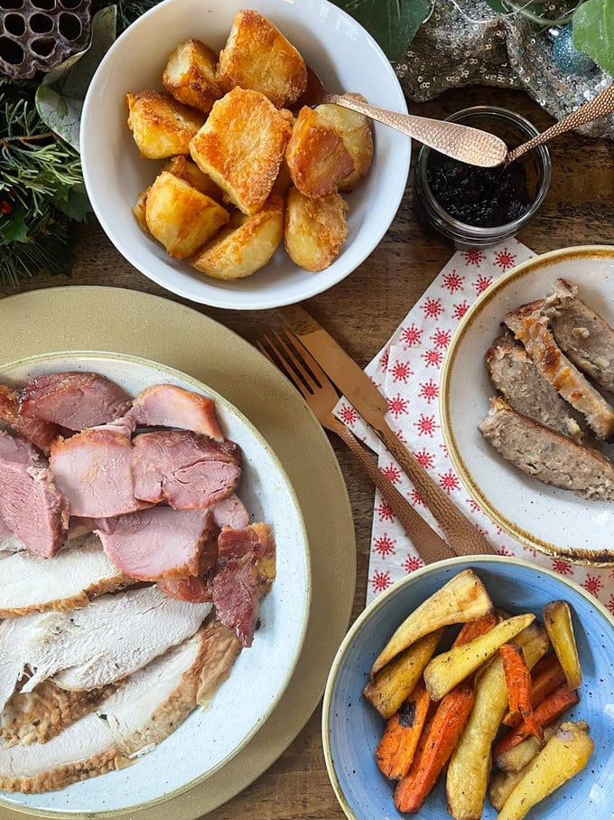 A Christmas feast laid out on a Christmas themed wooden table.