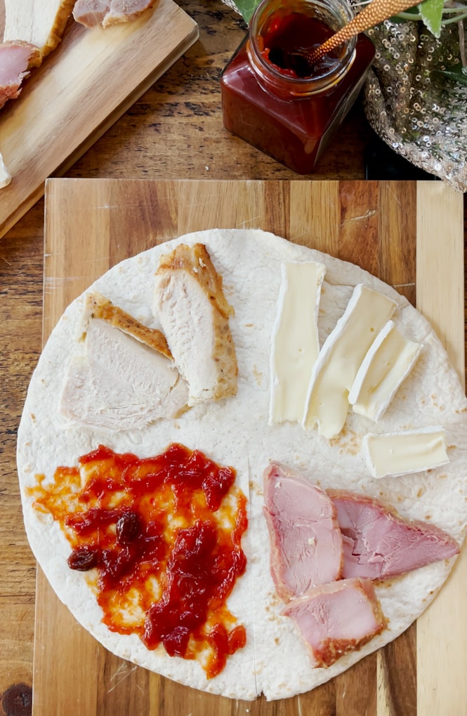 Placed open wraps on a wood work surface, added a leftover to a quarter of the wrap, we added chilli chutney, turkey, brie and ham.