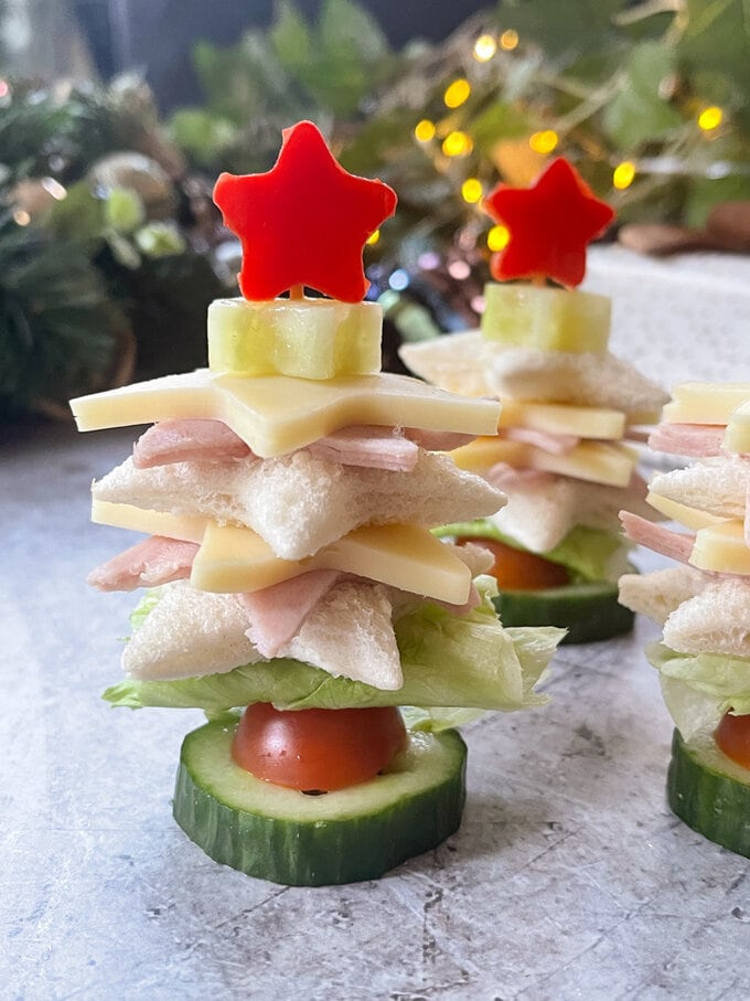 Close up on sandwich showing you the star shaped layers, with lettuce,cucumber and cherry tomatoes added to create the Christmas tree shape.