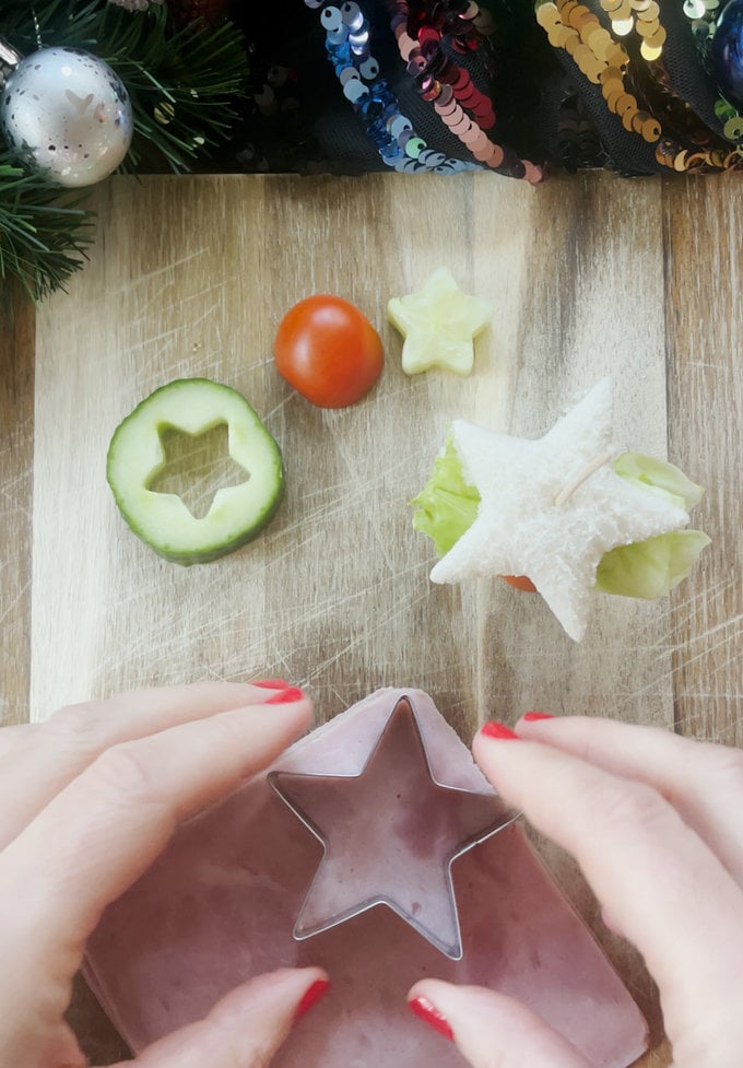 Tree sandwiches being constructed, using a cocktail stick. And a star shaped cookie cutter being used to shape the ham slices.