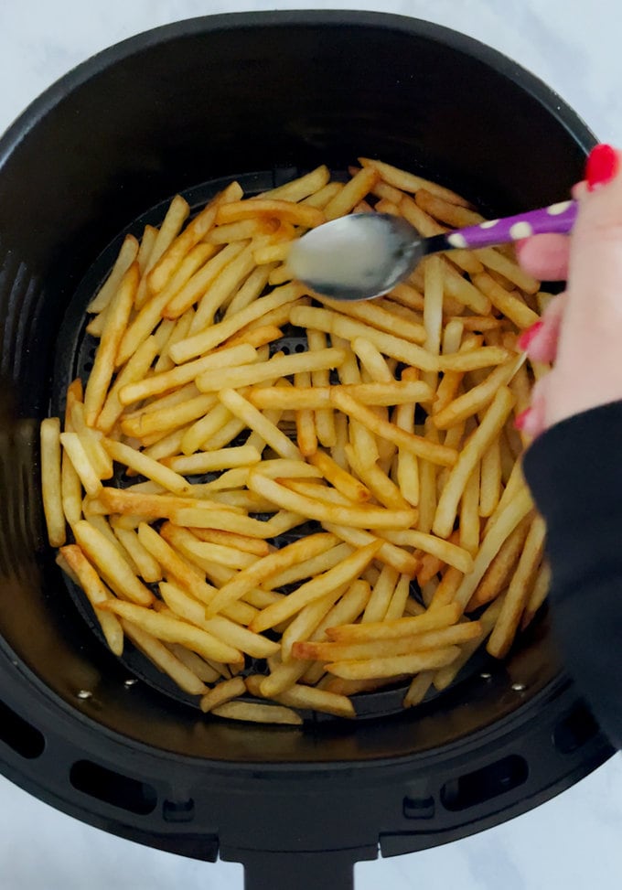 Melted butter bring poured onto cooked fries.