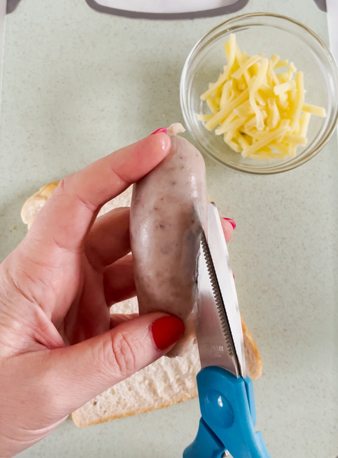 Sausages skins being removed using a pair of sissors.