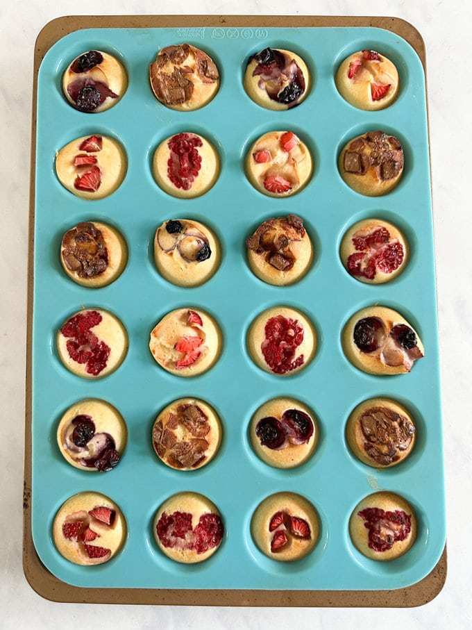 Blue silicone mini muffin tray with cooked mini pancake bites in it.