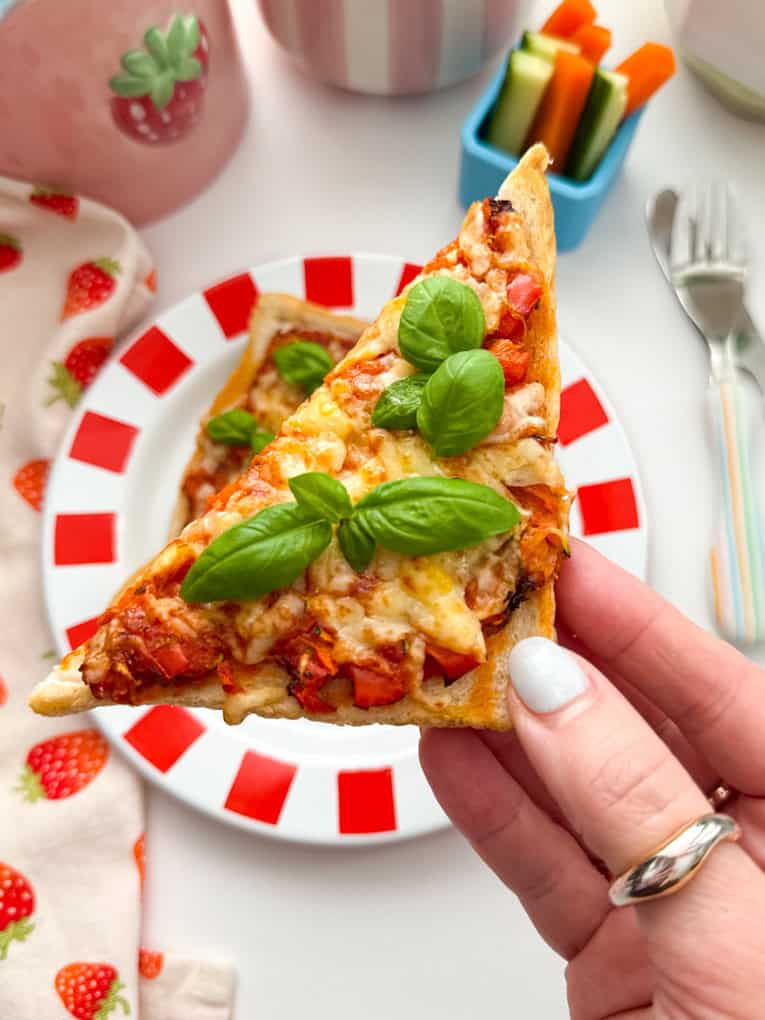 Close up photo of a triangle of Air Fryer Pizza Toast garnished with a sprig of basil.
