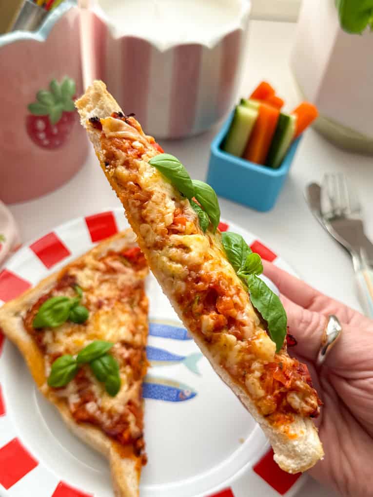 Close up photo of a triangle of Air Fryer Pizza Toast garnished with a sprig of basil.