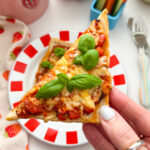 Close up photo of a triangle of Air Fryer Pizza Toast garnished with a sprig of basil.