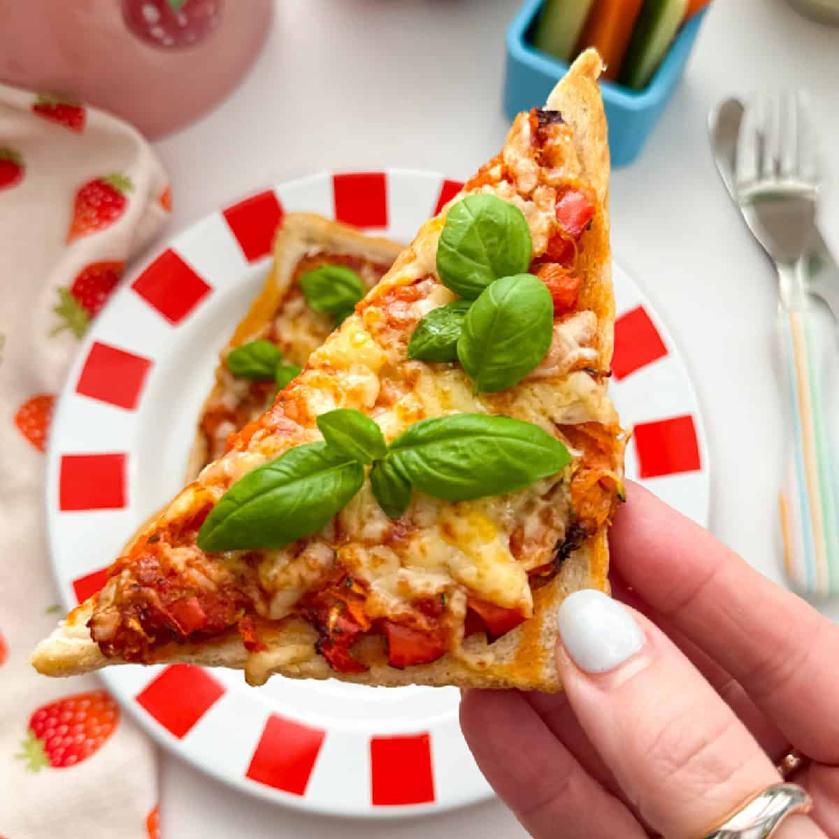 Close up photo of a triangle of Air Fryer Pizza Toast garnished with a sprig of basil.