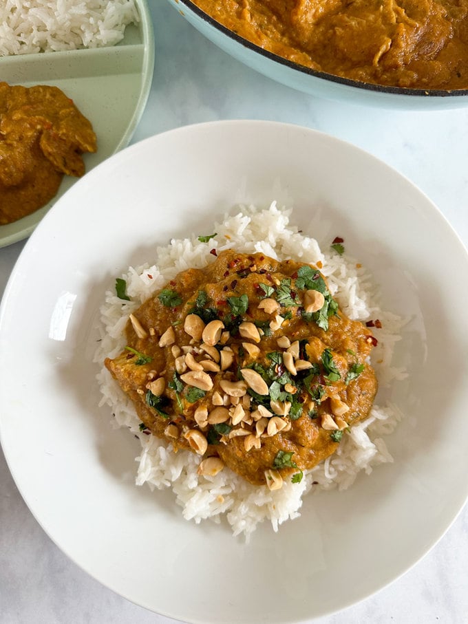 Hidden veg chicken satay, served in a white round bowl with a bed of white rice, and garnished with dried chili flakes,fresh coriander and crushed peanuts.  