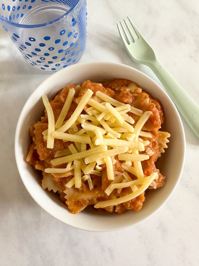 Slow cooker hidden vegetable and lentil sauce served over pasta, and garnished with grated cheese. 