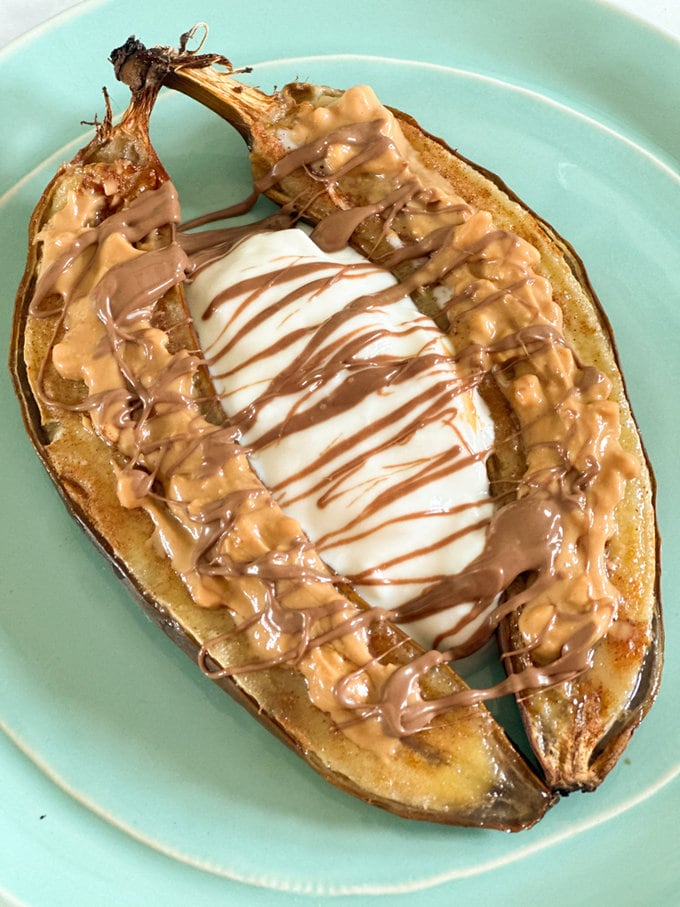 Airfryer snickers banana served in a light blue plat and garnished with peanut butter and chocolate.