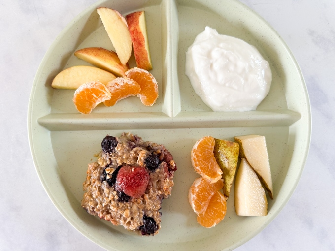 Easy Breakfast Recipes and Prep Ideas for Kids - Baked Berry Oats Bar served on a kid's shared plate with chopped apple, satsuma and Greek yogurt.