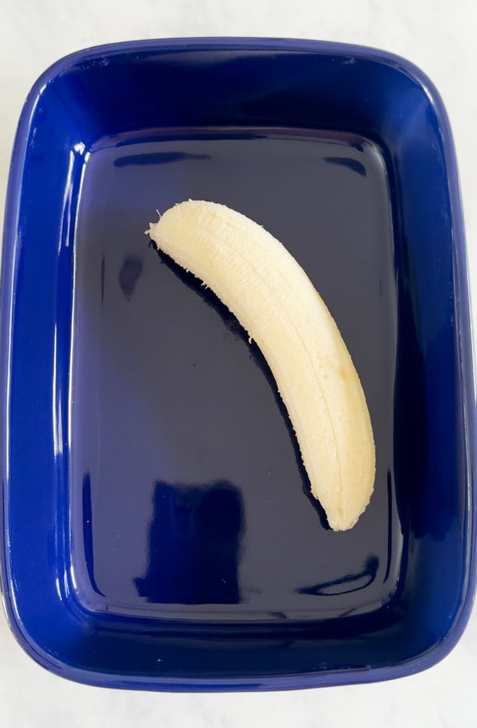 Peeled banana laying in a blue dish.