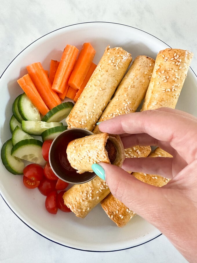 Airfryer cheats sausage rolls served in a round bowl along with fresh chopped carrots,cucumber and cherry tomatoes.
