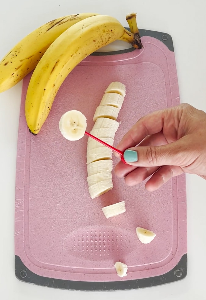 Small plastic food skewer being inserted into the banana slice.