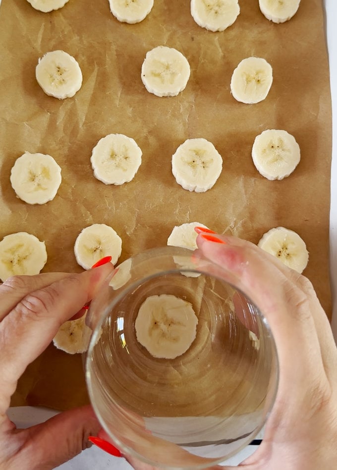 Banana slices placed on a baking tray with parchment paper underneath.