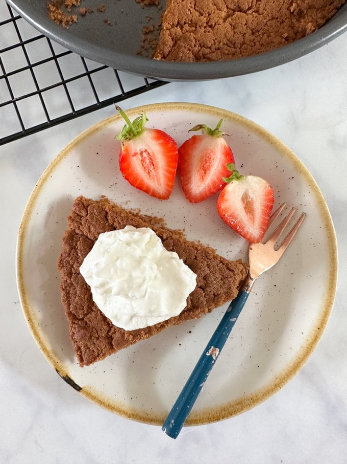 3 ingredient airfryer biscoff cake presented on a small round plate with a fork, and garnished with a dollop of Greek yogurt and summer berries. 