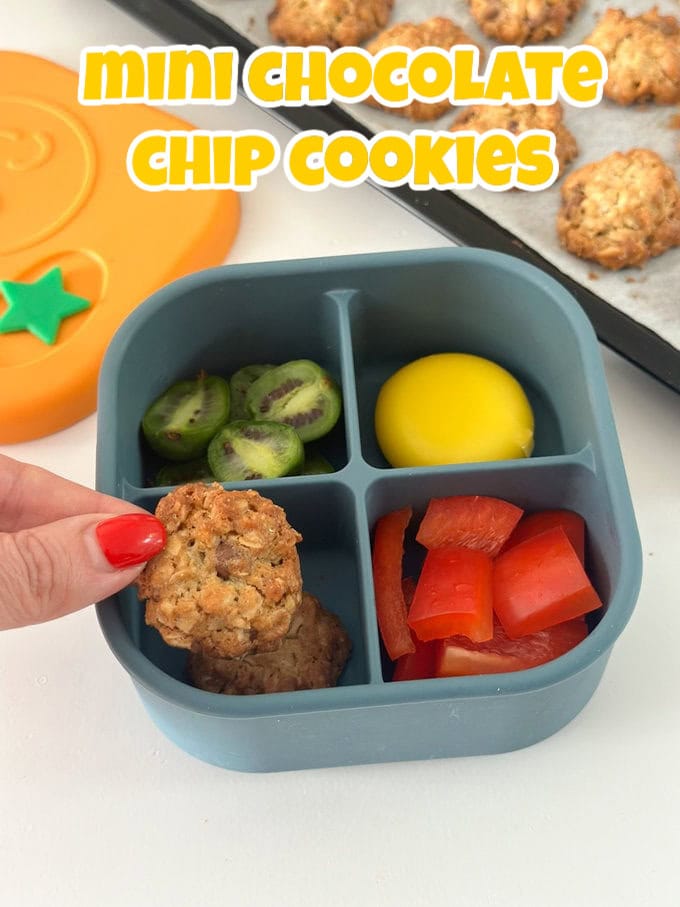 Two Mini Chocolate Chip Cookies in a blue divided snack box for kids from Pick Plates with mini kiwis, chopped red pepper and a mini cheese portion.