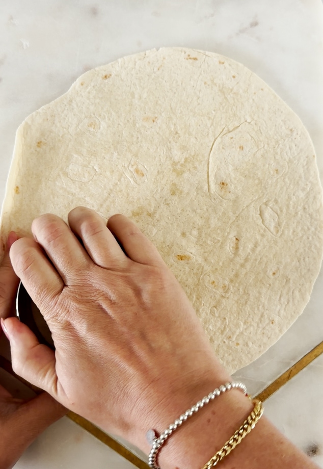 Six round circles being cut out of the tortilla wrap using a pastry cutter.