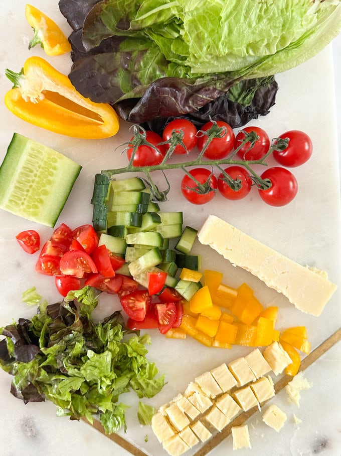 All the ingredients set out on a chopping board Bright and colorful fresh vegetables and cheese. ready to be added to the cups. 