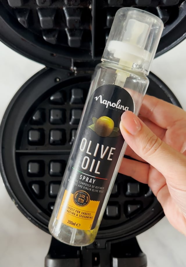 Olive oil being sprayed onto the waffle maker.